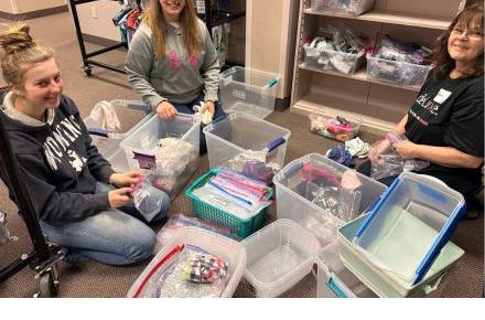 Three women sitting on the floor organizing socks