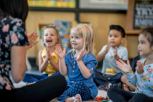 Children sitting on the floor clapping their hands 